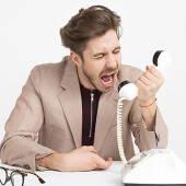Frustrated man yelling into phone - Broadband provider top complaints